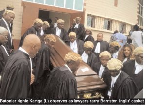 Batonier Ngnie Kamga (L) observes as lawyers carry Barrister  Inglis’ casket