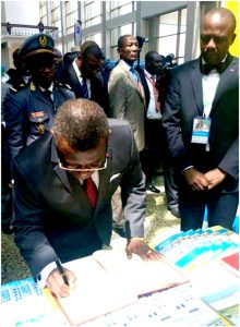  PM Dion Ngute signs FEICOM golden book as DG, Camille Akoa looks on 