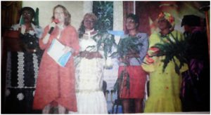 UN System Representative flanked by Cameroonian women holding peace plants 